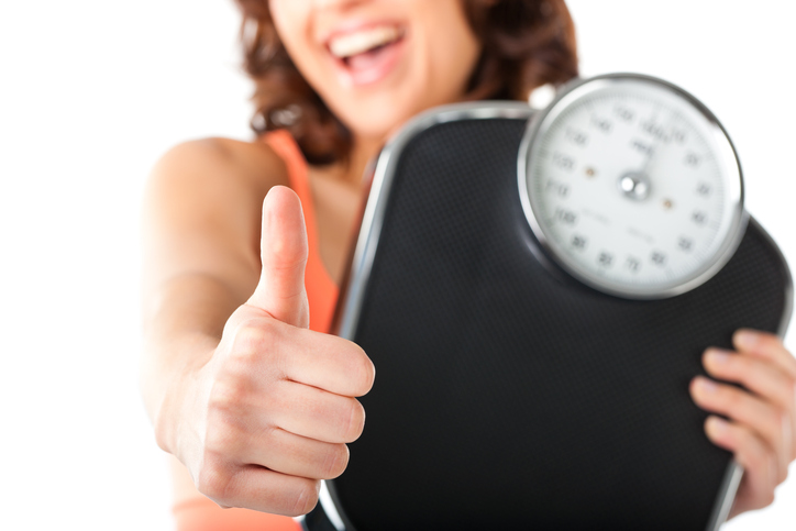 Woman holding scale and thumbs up