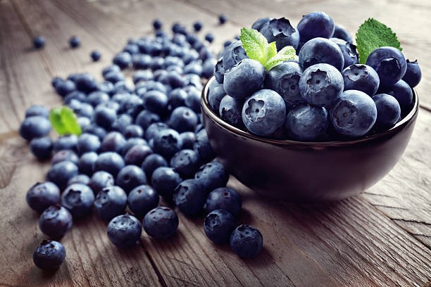 Blueberries in a bowl and on a wooden table