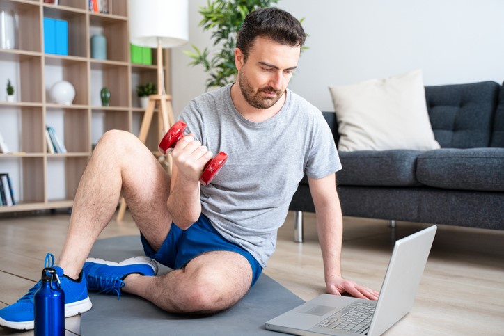 Man working out next to computer with dumbbells