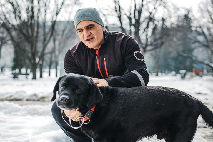 Man petting dog outside in the snow